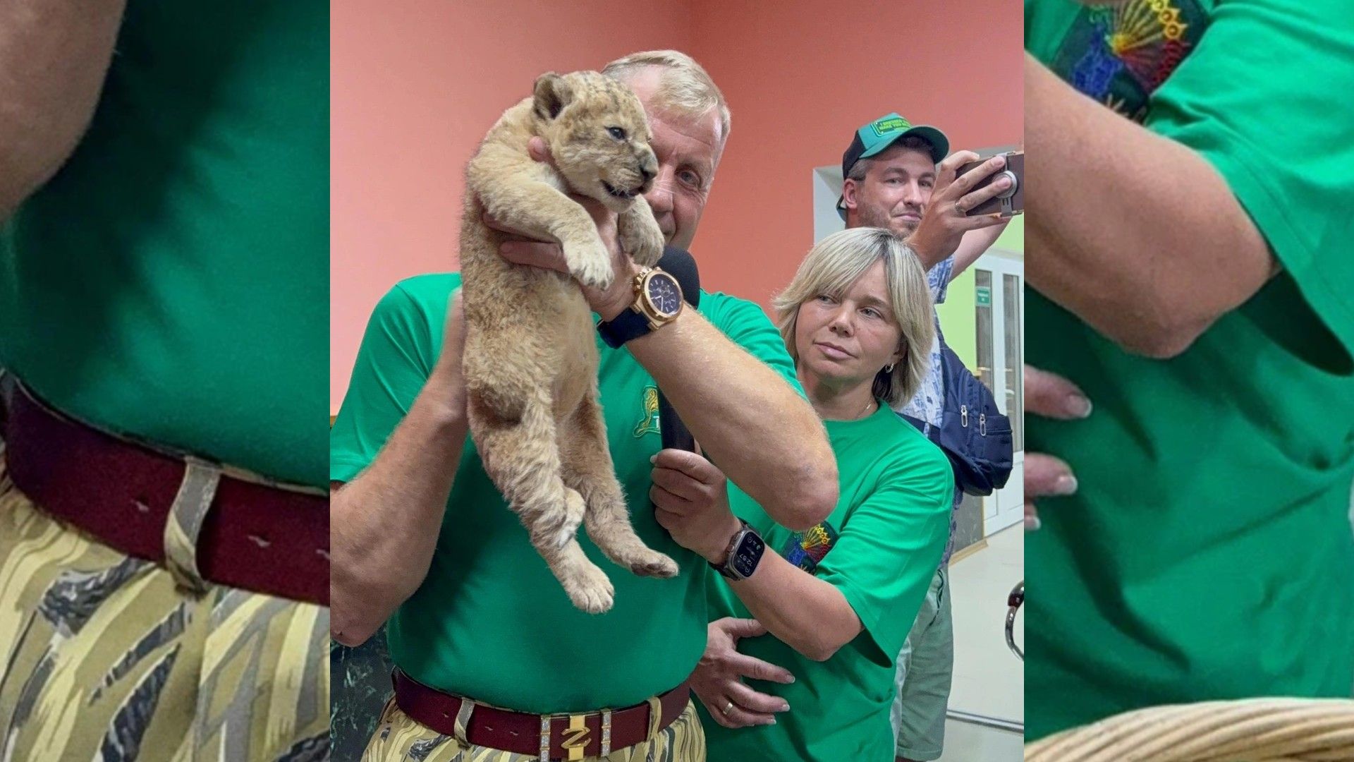 Олег Зубков в зелёной футболке держит в руках львёнка